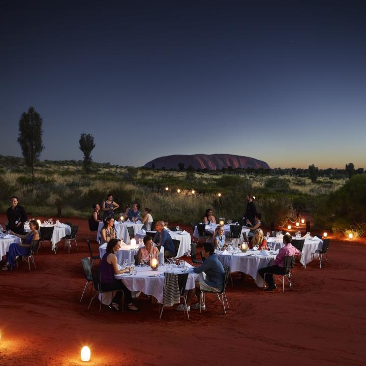 Diners at white-linen tables dining outdoors near Ayers rock